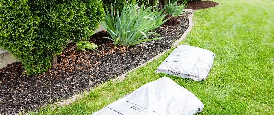 Bags of mulch near a landscape bed on a lawn in Carmel, IN.