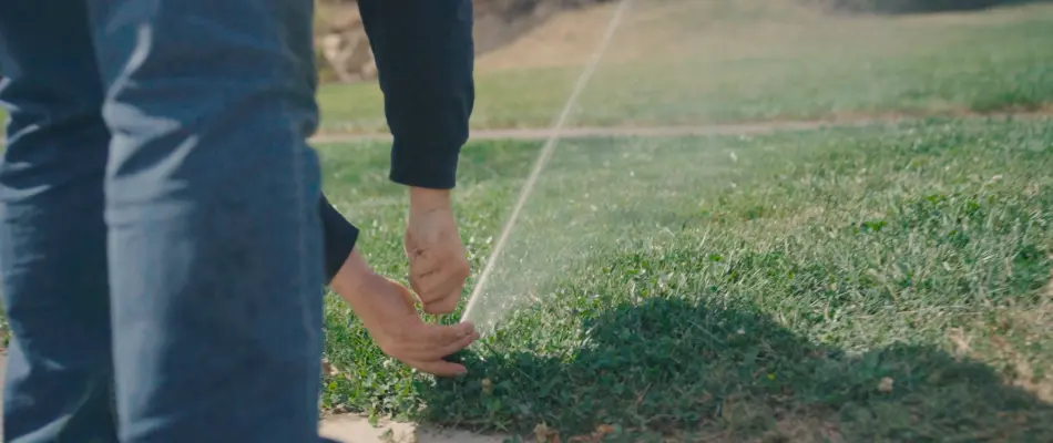 Adjusting a sprinkler head near a property in Meridian Hills, IN.