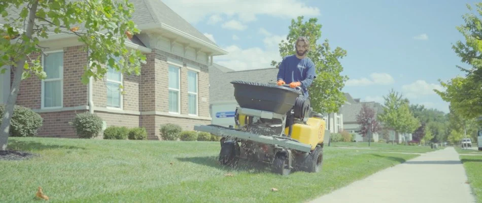 Professional in Carmel, IN, fertilizing grass.