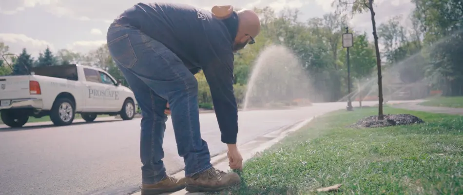 Irrigation repair man taking a look at a sprinkler head in Carmel, IN.